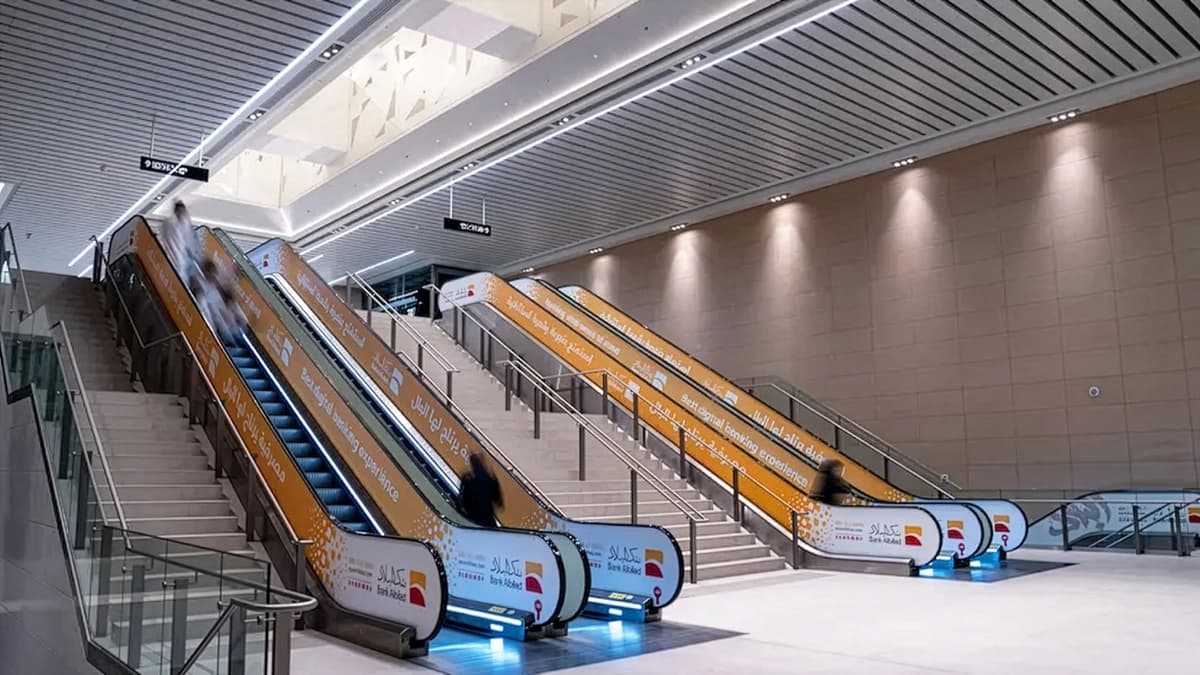 Escalator handrail sticker advertising in a Saudi metro station
